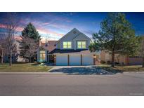 Charming two-story home features a 3-car garage, lush lawn, and well-maintained landscaping under a beautiful evening sky at 7340 Brixham Cir, Castle Pines, CO 80108