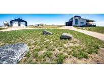Modern home exterior featuring a spacious yard, garage, and additional storage building at 43010 Ptarmigan Ranch St, Parker, CO 80138