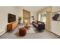 Comfortable living room featuring a brick fireplace, plush sofa, and natural light at 18022 E Loyola Pl, Aurora, CO 80013