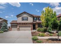 Two-story home featuring a three-car garage, stone accents, and landscaped front yard on a sunny day at 19347 E 65Th Ave, Aurora, CO 80019