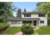 Inviting two-story home showcasing a manicured lawn and brick pathway leading to the covered front porch at 11880 W 30Th Pl, Lakewood, CO 80215