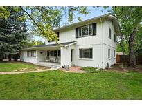 Charming two-story home featuring a brick-and-wood facade and a welcoming front porch, surrounded by lush greenery at 11880 W 30Th Pl, Lakewood, CO 80215