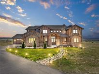 A sprawling rustic home with stone and wood finishes, a stone walkway, and a well-manicured lawn at 1587 Arrowpoint Ct, Franktown, CO 80116