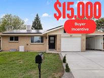 Ranch style home with solar panels, attached garage, and landscaped yard at 5329 Flower Cir, Arvada, CO 80002