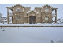 Condominium exterior with stone facade and snow-covered grounds, creating a cozy winter scene at 7440 S Blackhawk St # 9-108, Englewood, CO 80112