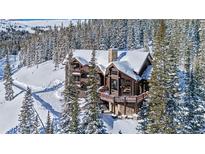 Stunning log cabin home surrounded by snow-covered trees, featuring a stone foundation and inviting balconies at 351 Kimmes Ln, Breckenridge, CO 80424