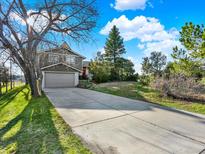 Charming two-story home featuring an attached garage, long driveway, and a large tree in the front yard at 12798 Tomahawk Rd, Parker, CO 80138