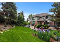 Expansive backyard featuring a large lawn, mature trees, patio with seating, and beautiful landscaping at 6132 S Boston Cir, Greenwood Village, CO 80111