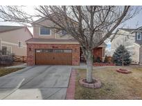 Charming two-story home features a red brick facade, a two-car garage, and a well-maintained front yard at 11701 Elkhart St, Commerce City, CO 80603