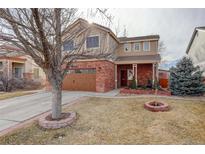 Inviting two-story home with a brick facade, a manicured lawn, and an American flag at 11701 Elkhart St, Commerce City, CO 80603