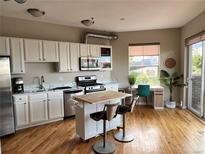 Modern kitchen featuring white cabinets, stainless steel appliances, and an island with bar seating at 1441 Central # 305, Denver, CO 80211