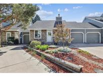Charming home featuring stone and gray wood siding, a landscaped yard, and an attached two-car garage at 4720 S Dudley St # 38, Littleton, CO 80123