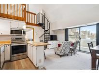 Bright open-concept living area with vaulted ceilings, spiral staircase, and a sliding glass door with balcony access at 5250 S Huron Way # 5-308, Littleton, CO 80120
