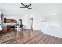 A spacious living room and kitchen are shown with wood floors and white walls at 5571 Killarney St, Denver, CO 80249