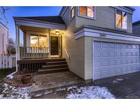 Charming two-story home with a covered porch and attached two-car garage at dusk at 2697 S Deframe Cir, Lakewood, CO 80228