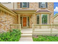 Inviting front entrance featuring a covered porch, bay window, and brick exterior at 2316 Weatherstone Cir, Highlands Ranch, CO 80126