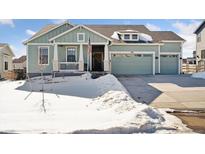 Two-story house with a light green exterior, two-car garage, and a snowy front yard at 1030 W Hopkins Dr, Elizabeth, CO 80107