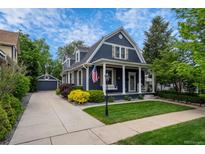Charming blue two-story home with a manicured lawn, inviting porch swing, and detached garage with concrete driveway at 5675 S Crocker St, Littleton, CO 80120