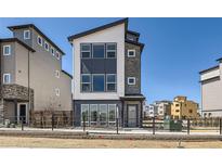 Modern three-story home with a sleek design, large windows, and a well-maintained front yard at 10863 E Hinsdale Cir, Centennial, CO 80112