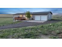 Single story gray house with a wood deck, two-car garage, and lawn at 11100 Haskell Creek Rd, Larkspur, CO 80118
