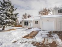 Charming home exterior with a driveway and garage covered in fresh snow at 16390 E Radcliff Pl # B, Aurora, CO 80015