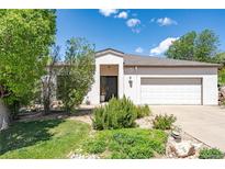 Attractive single-story home featuring a well-manicured front yard, mature trees, and an attached two-car garage at 330 Ptarmigan St, Golden, CO 80403