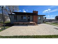 Charming single-story home featuring a spacious front patio, brick chimney, and well-maintained landscaping at 15600 E 33Rd Pl, Aurora, CO 80011