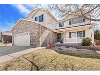 Charming two-story home features brick accents, a well-manicured lawn, and a cozy front porch at 11274 W 54Th Ln, Arvada, CO 80002