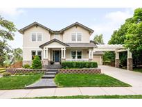 Charming two-story home featuring a well-manicured front yard, inviting entrance, and an attached garage with a pergola-covered driveway at 6032 Umber St, Arvada, CO 80403