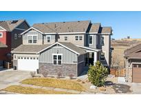 Beautiful two-story home featuring gray siding, stone accents, a well-manicured lawn and an attached two car garage at 17577 W 87Th Ave, Arvada, CO 80007