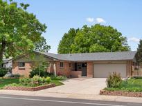 Charming brick ranch-style home featuring mature trees, landscaped yard and attached two-car garage at 945 Emerald St, Broomfield, CO 80020