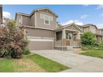 Charming two-story home with a two-car garage, inviting front porch with stone accents and beautifully landscaped front yard at 6484 N Ceylon Ct, Denver, CO 80249