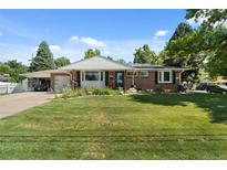 Charming brick home featuring a well-maintained lawn, garden area, and convenient carport at 105 Dudley St, Lakewood, CO 80226