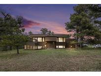 Stunning two-story home with beautiful architecture surrounded by lush landscaping and a colorful sky at 22453 Hillcrest Cir, Golden, CO 80401