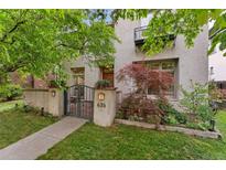 Charming home with a stucco exterior, well-manicured lawn, beautiful landscaping, and inviting front gate at 635 N Williams St, Denver, CO 80218