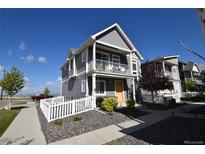 Charming two-story home featuring a balcony, gray siding, white picket fence, and rock landscaping at 17747 E 54Th Ave, Denver, CO 80249