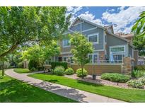 Inviting townhome with lush landscaping, mature trees, and a charming walkway leading to the entrance at 14300 Waterside Ln # E3, Broomfield, CO 80023