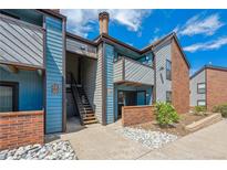 Charming condo exterior with blue siding, brick accents, and well-maintained landscaping under a bright sky at 12037 E Harvard Ave # 104, Aurora, CO 80014