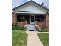 Charming brick home featuring a covered front porch and well-maintained lawn and walkway at 4654 Bryant St, Denver, CO 80211