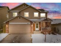 Charming two-story home with a two-car garage and a cozy front porch, surrounded by a snow-covered yard at 4821 N Silverlace Dr, Castle Rock, CO 80109