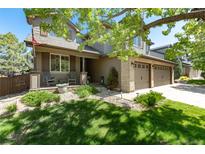 Charming two-story home featuring a well-manicured lawn, mature trees, and an inviting front porch with rocking chairs at 3791 Charterwood Cir, Highlands Ranch, CO 80126