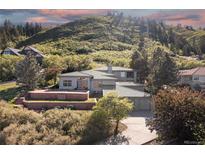 Stunning exterior elevation of home situated on a terraced lot with mountain views and mature trees at 11039 Roxborough Dr, Littleton, CO 80125