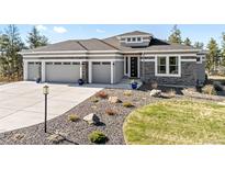 Beautiful home exterior with stone accents, a three-car garage, and drought resistant landscaping at 445 Panoramic Dr, Monument, CO 80132