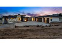 Contemporary home featuring a stone facade, multiple garage doors, and concrete driveway at dusk at 545 Strada Rossa Rd, Golden, CO 80401