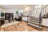 Open living room with hardwood floors, fireplace, and staircase to the upper level at 1348 E Jamison Ave, Centennial, CO 80122