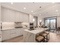 Modern kitchen with stainless steel appliances, a large island with seating, and sleek white cabinetry at 1901 Wazee St # 807, Denver, CO 80202