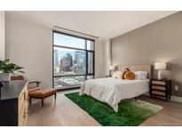 Bright bedroom featuring a large window showcasing the city skyline and comfortable furnishings at 1901 Wazee St # 807, Denver, CO 80202