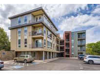 Modern condo building with tan and grey facade, multiple balconies, and convenient parking at 5201 S Fox St # 102, Littleton, CO 80120