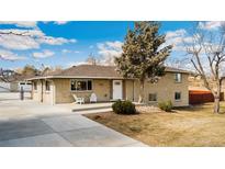 Charming brick home featuring a well-manicured front yard and a cozy front porch with seating for guests at 7339 Carr St, Arvada, CO 80005
