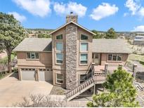 Charming two-story home featuring a stone chimney, two-car garage, and an inviting elevated deck with mountain views at 18750 Spring Valley Rd, Monument, CO 80132